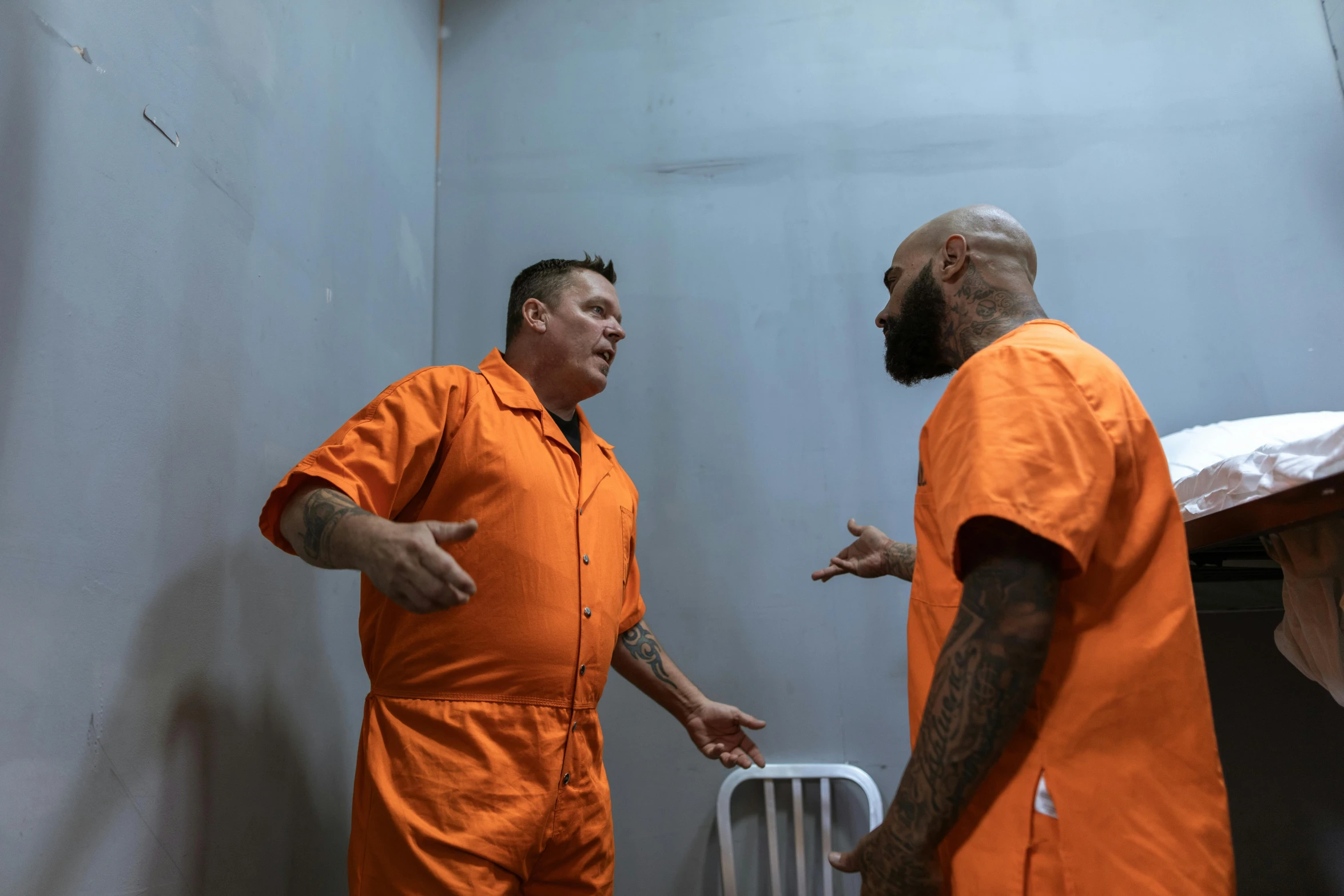 two men in orange prison suits are talking and laughing