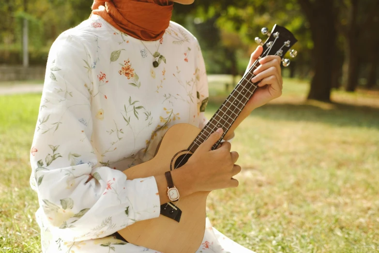 a person is holding a wooden guitar in the park