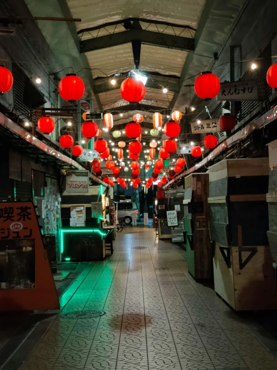 a long dark room with red lanterns hanging from the ceiling