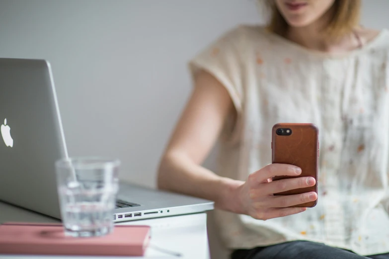 woman with cell phone and laptop in an office