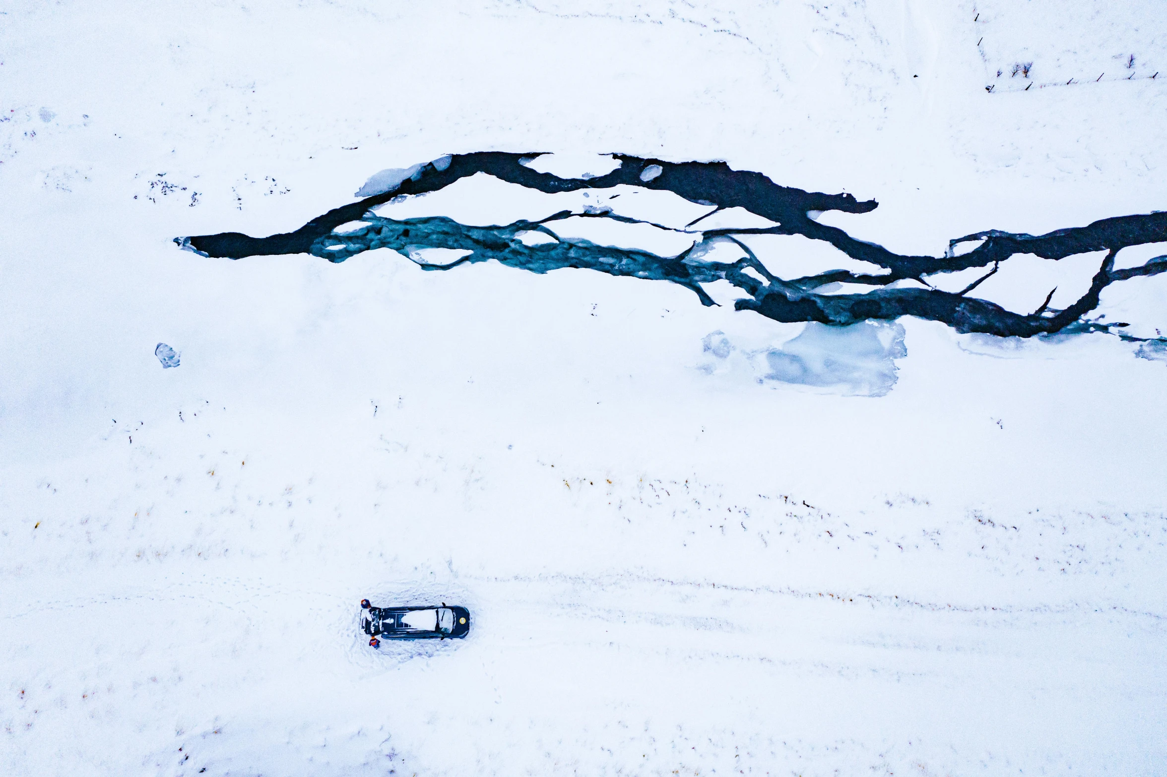 a small car parked in the snow near some nches