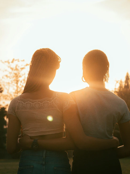 two people are looking at the sun with their backs to the camera