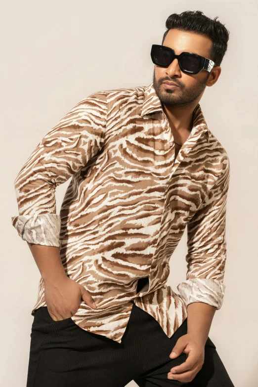 man with sunglasses posing for picture while wearing animal print shirt