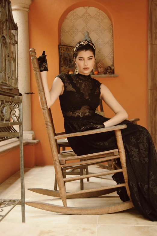 a woman in a black dress sits on a rocking chair