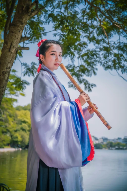 a girl with a fan holds on to a stick near the water