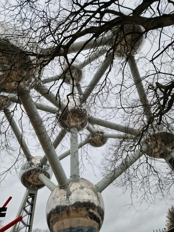 large metal object near barren trees in a large city