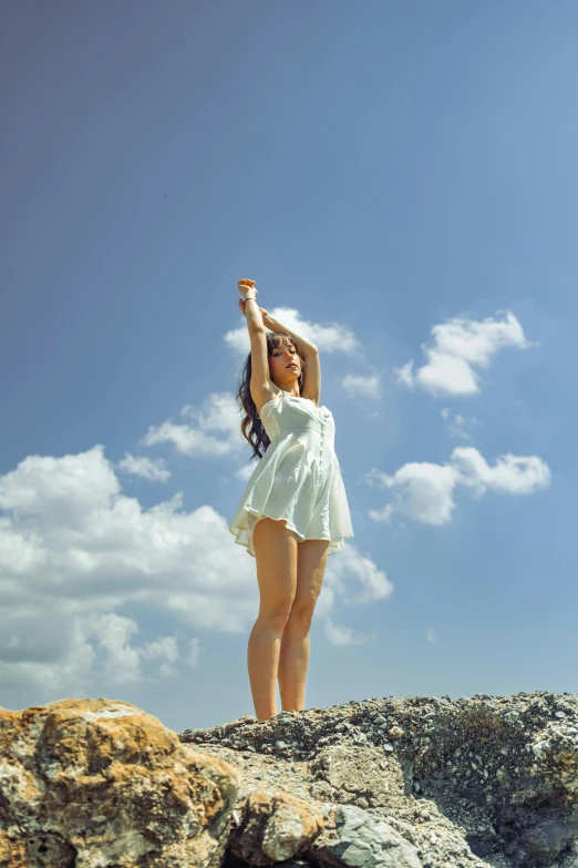 a woman standing on top of a rock holding a kite