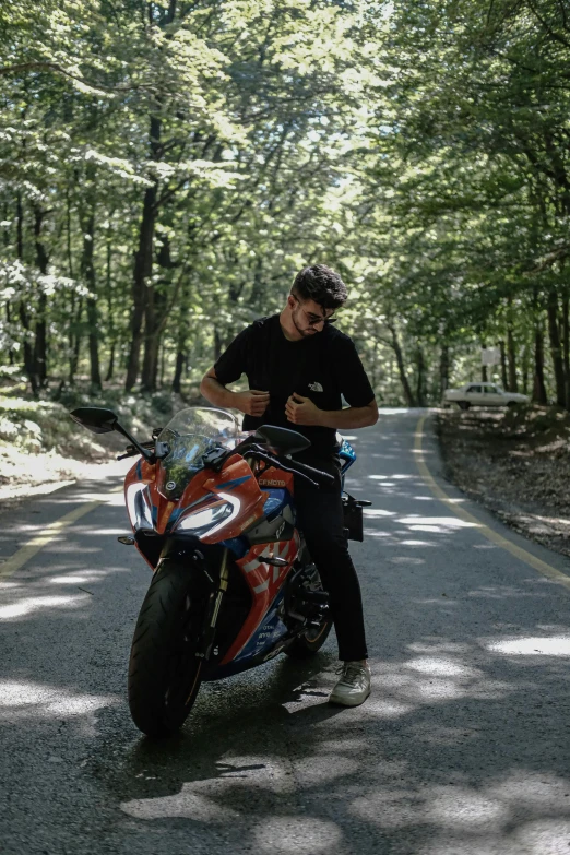 the young man is sitting on his motorcycle reading his cell phone