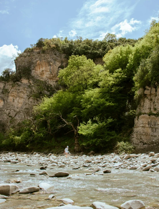 the man stands on the river bank in the rocks