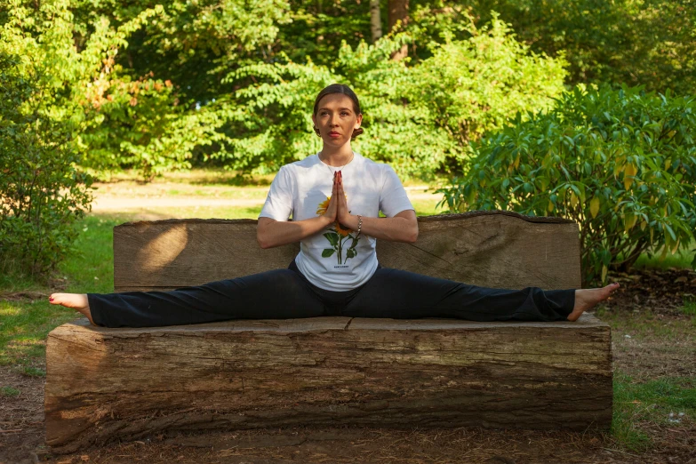 a man sitting on a park bench doing yoga