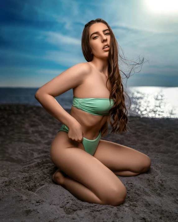 an artistic pograph of a woman in green bikini sitting on the beach