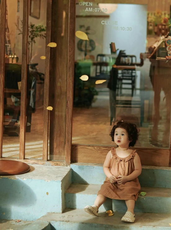 an older toddler sits on some stairs and looks at the camera