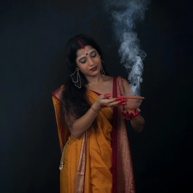 a woman in sari holding a cigarette in her hands