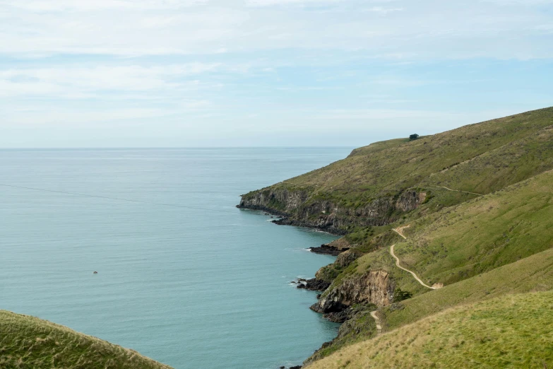 a view of the sea from atop a grassy hill