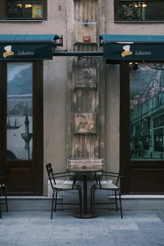 an old building with windows, two chairs and a table