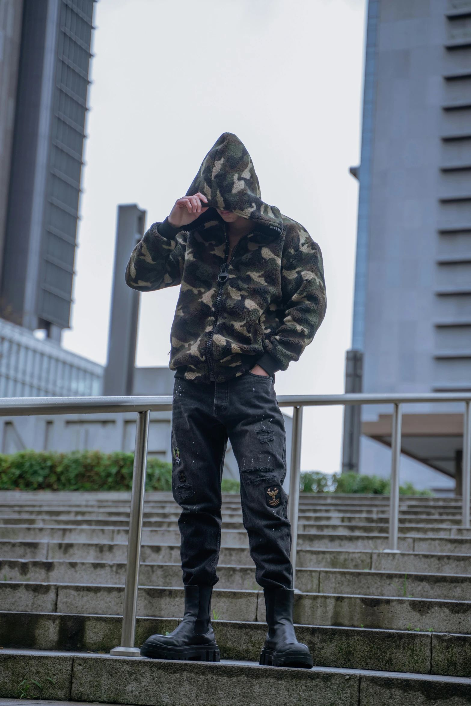man standing on steps wearing camouflage coat and jeans