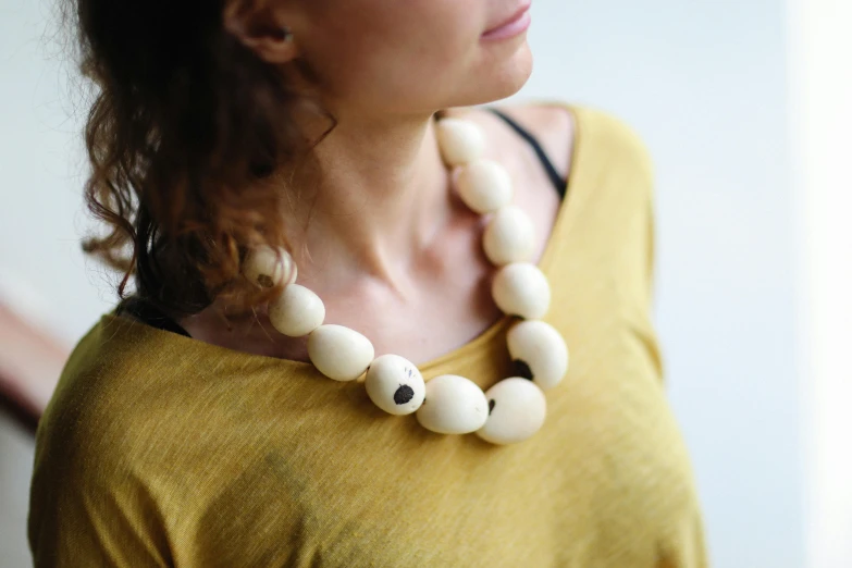 a woman in a yellow shirt with a necklace