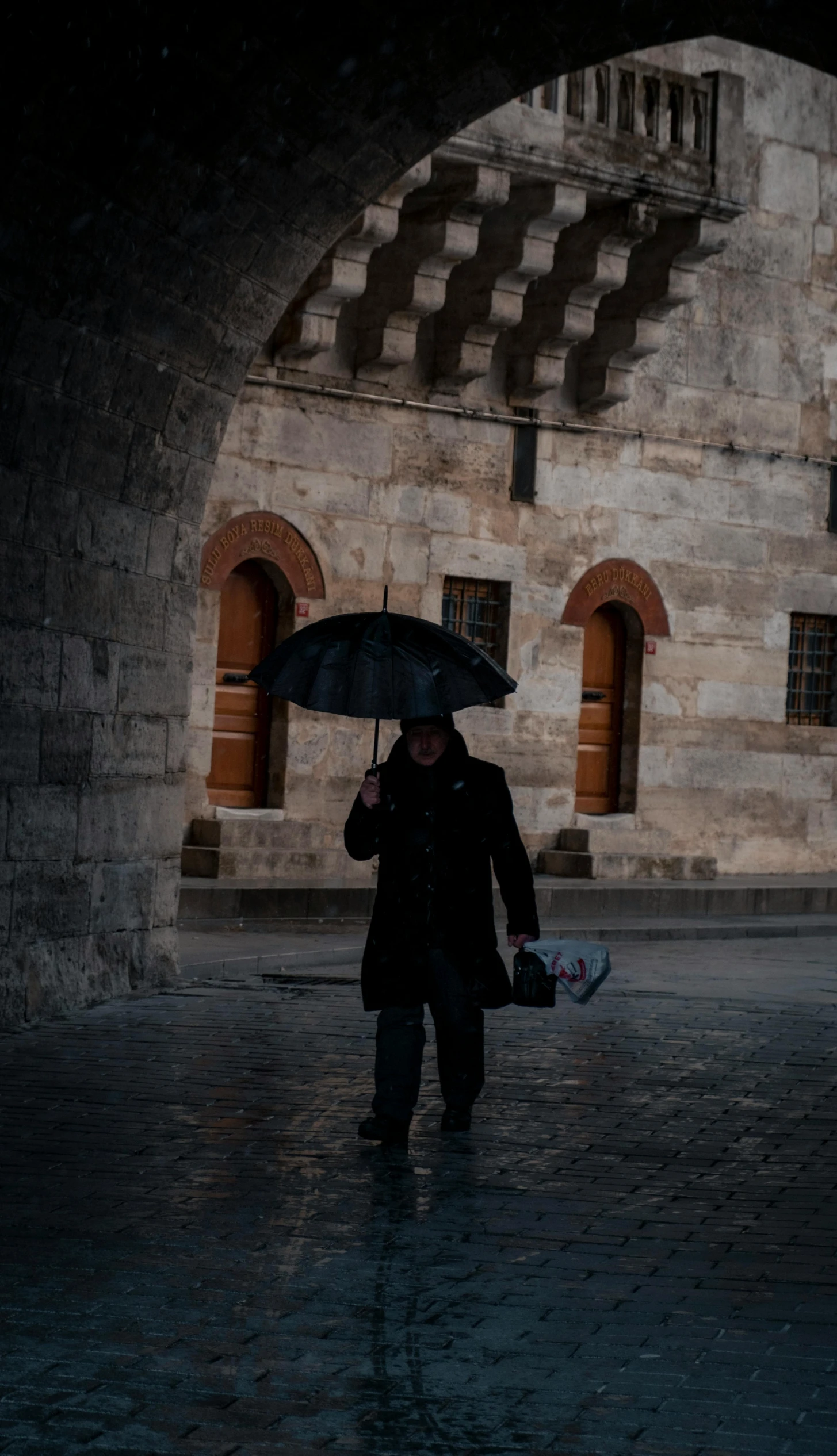 a man walking in the rain holding an umbrella