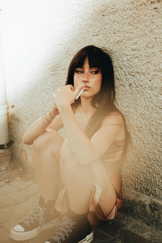 a beautiful young lady sitting on the floor smoking a cigarette