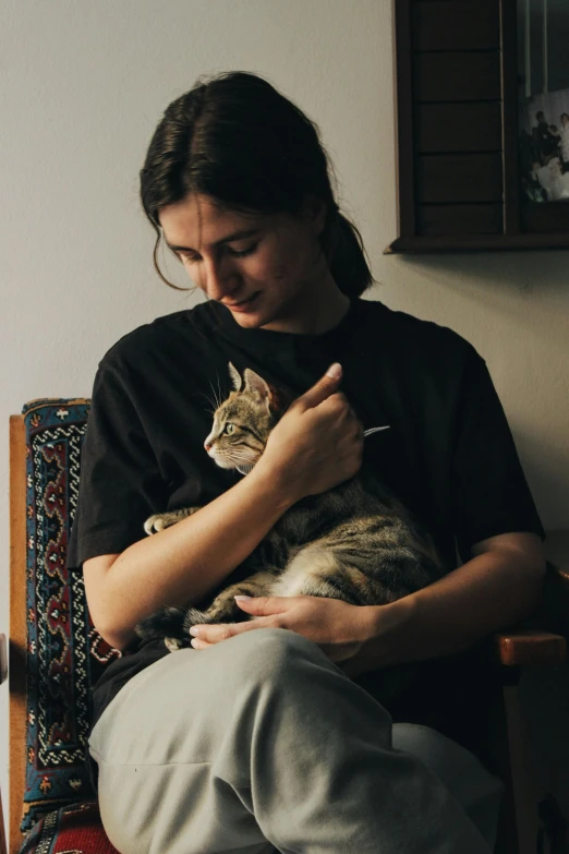 a person sitting on a chair holding a cat