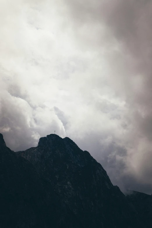 the top of a mountain is covered by dark clouds