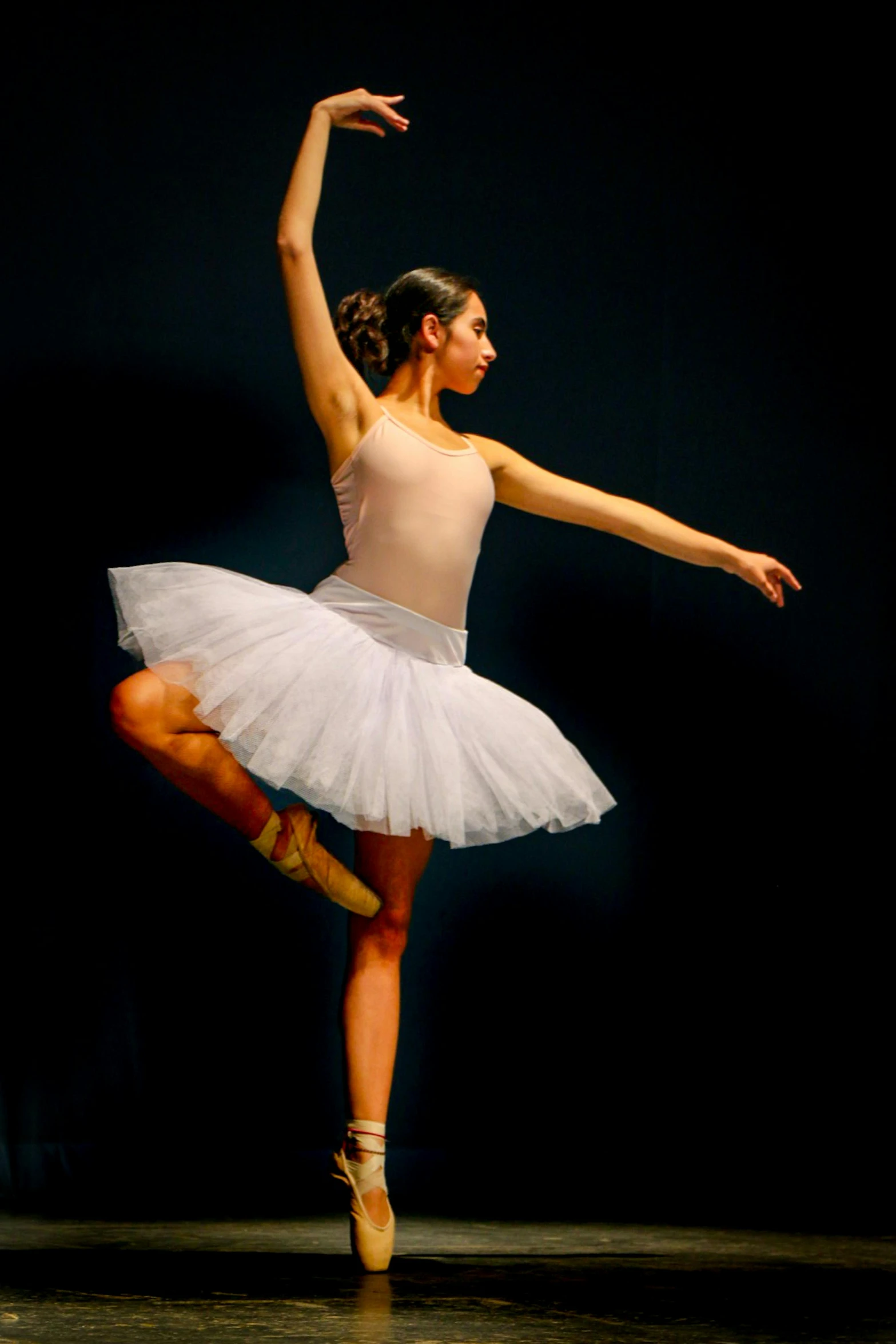 a ballet dancer standing on one leg, and holding her arm in the air