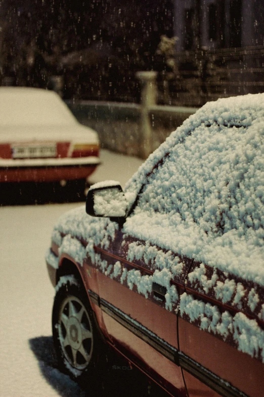 two cars covered with snow in front of building