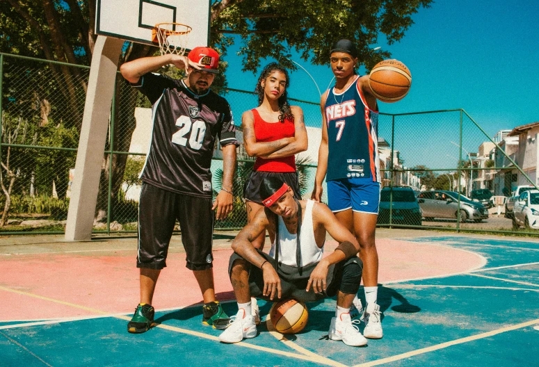 a man is holding a basketball while two girls are standing and one man sits in front of the basket