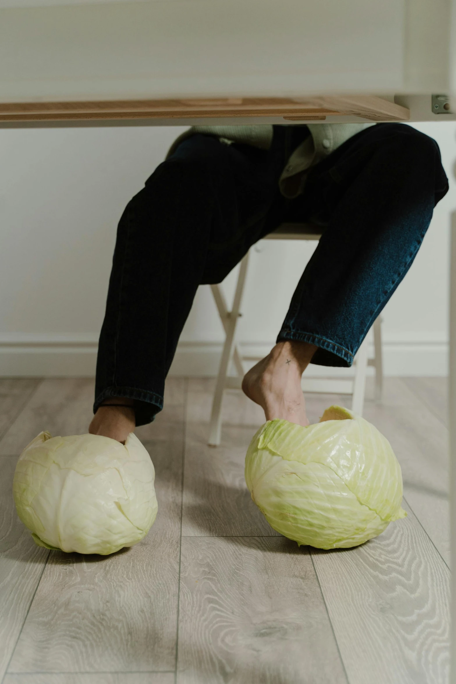 person sitting on a chair while on the floor holding a large ball with their feet