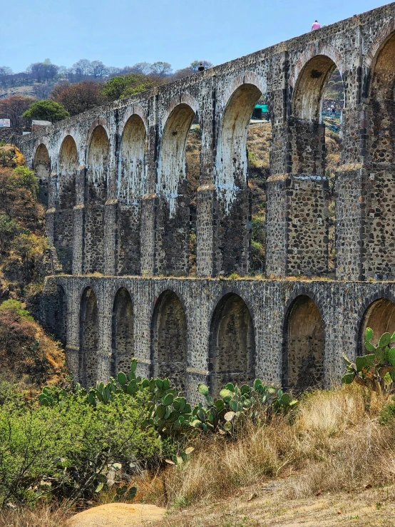 several arches form an old structure on top of a hill