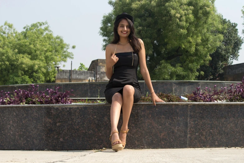 a women sitting on a wall posing for the camera