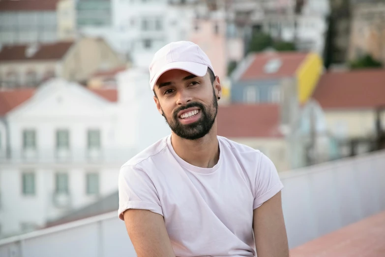 a man in a white cap sits on a metal rail