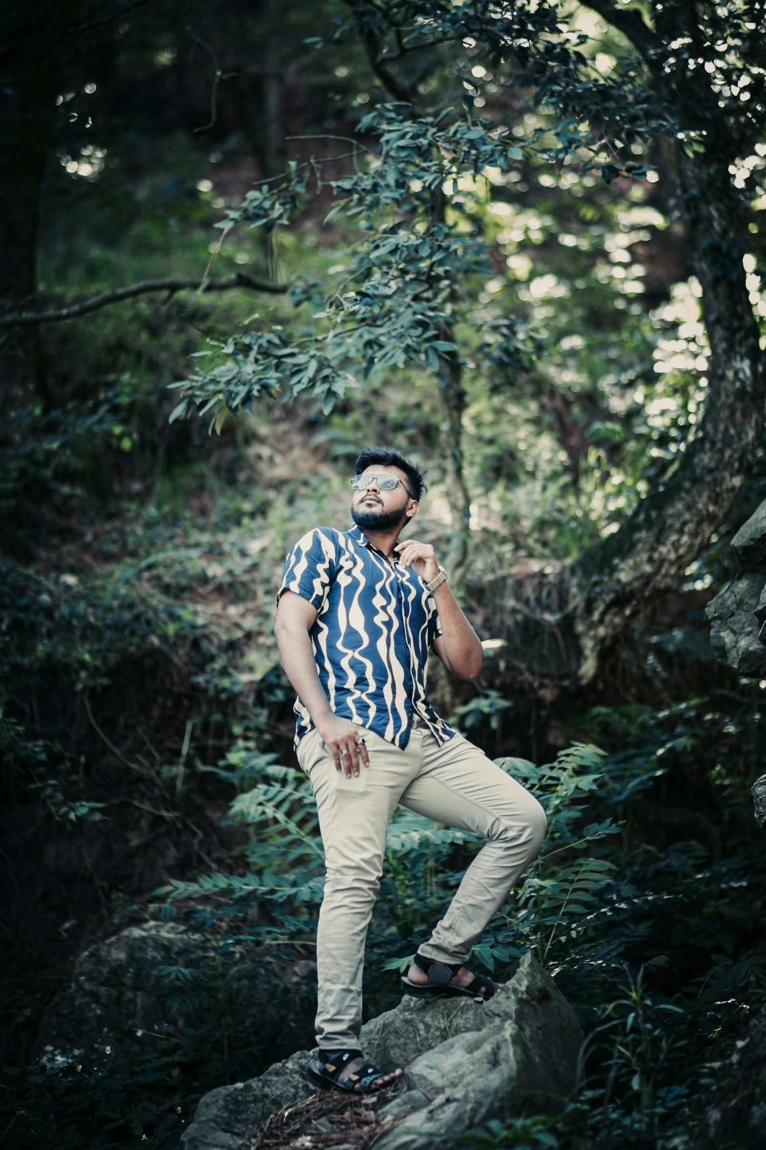 a man in striped shirt standing on a rock