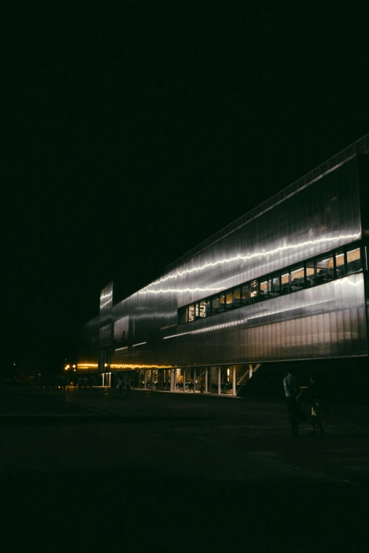 people walking outside a tall building at night