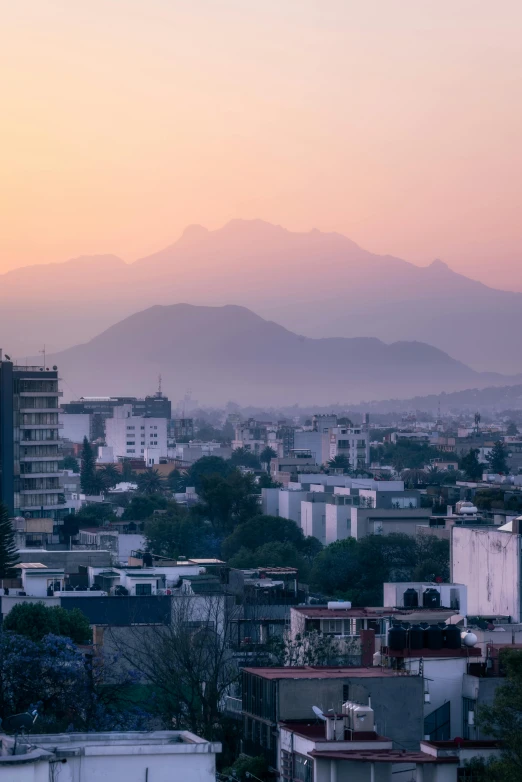 a hazy view of buildings, mountains and a city below them