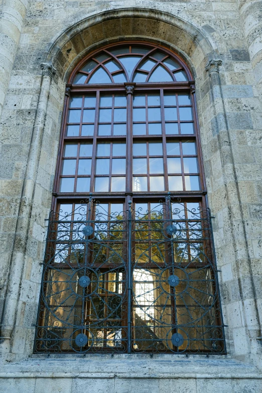 an open window with bars on top and a tree outside