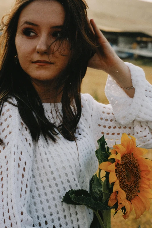 a woman posing for a po holding a sunflower