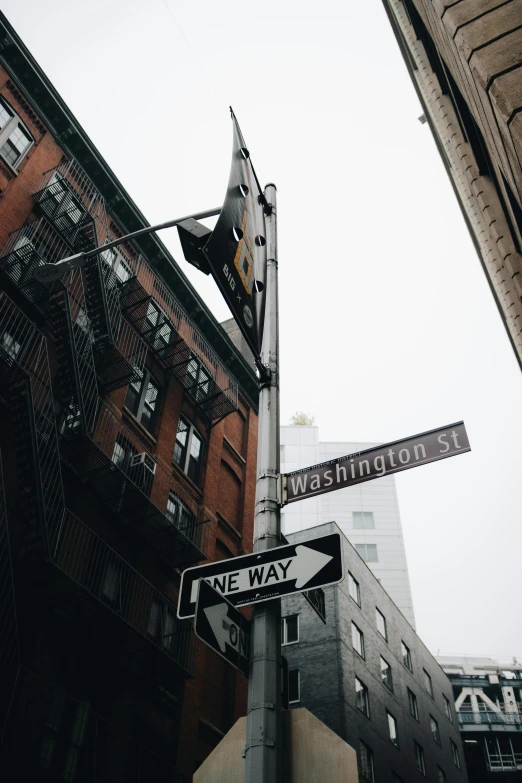 a one way sign is hanging on the side of a building