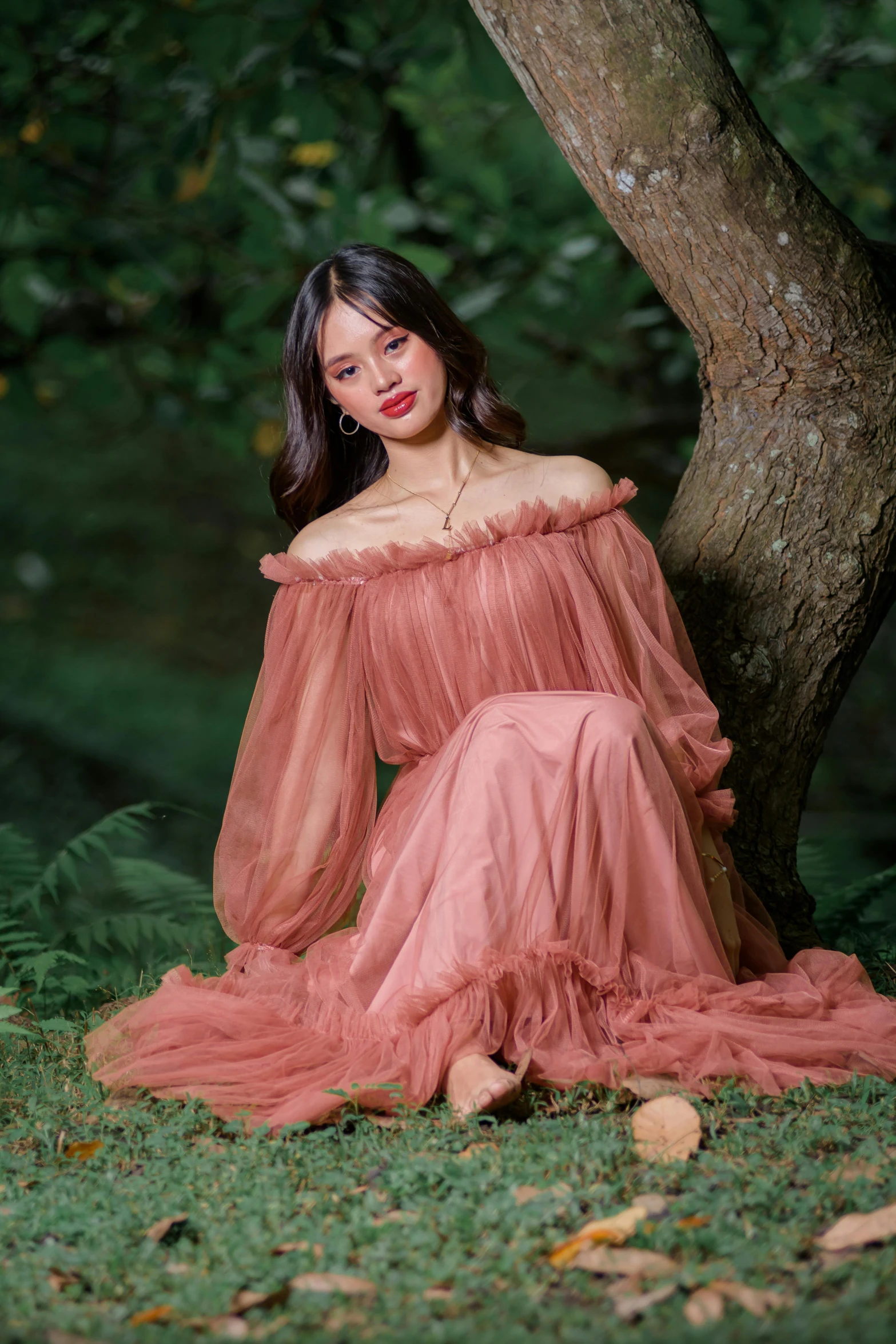 a woman in a dress poses under a tree