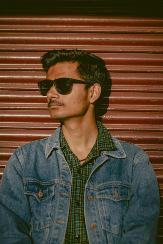 a man wearing sunglasses and a denim jacket