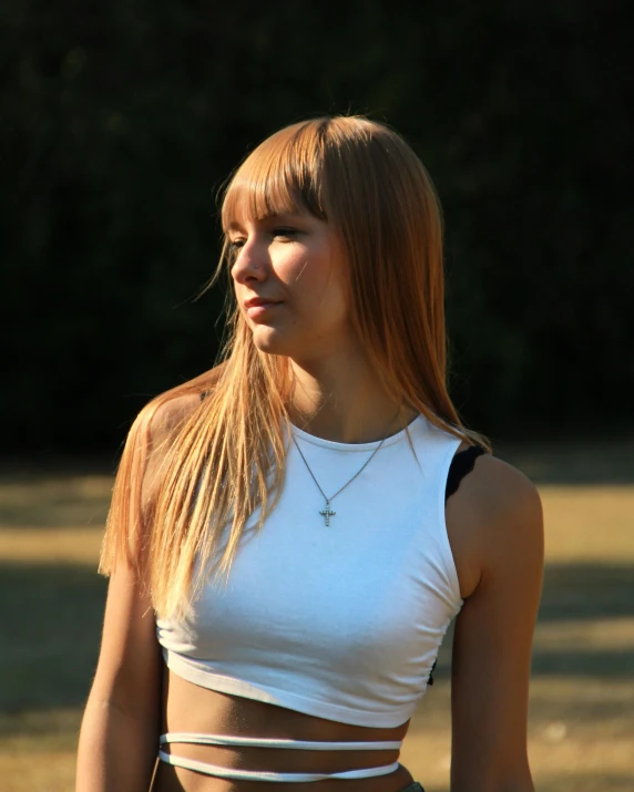 a young woman standing in a field with her arms crossed