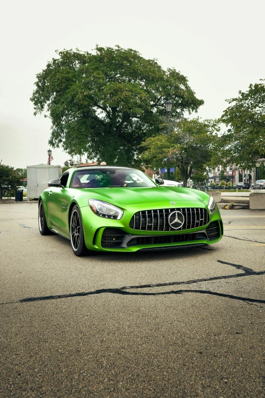 the green mercedes amg roadster car is parked in a parking lot