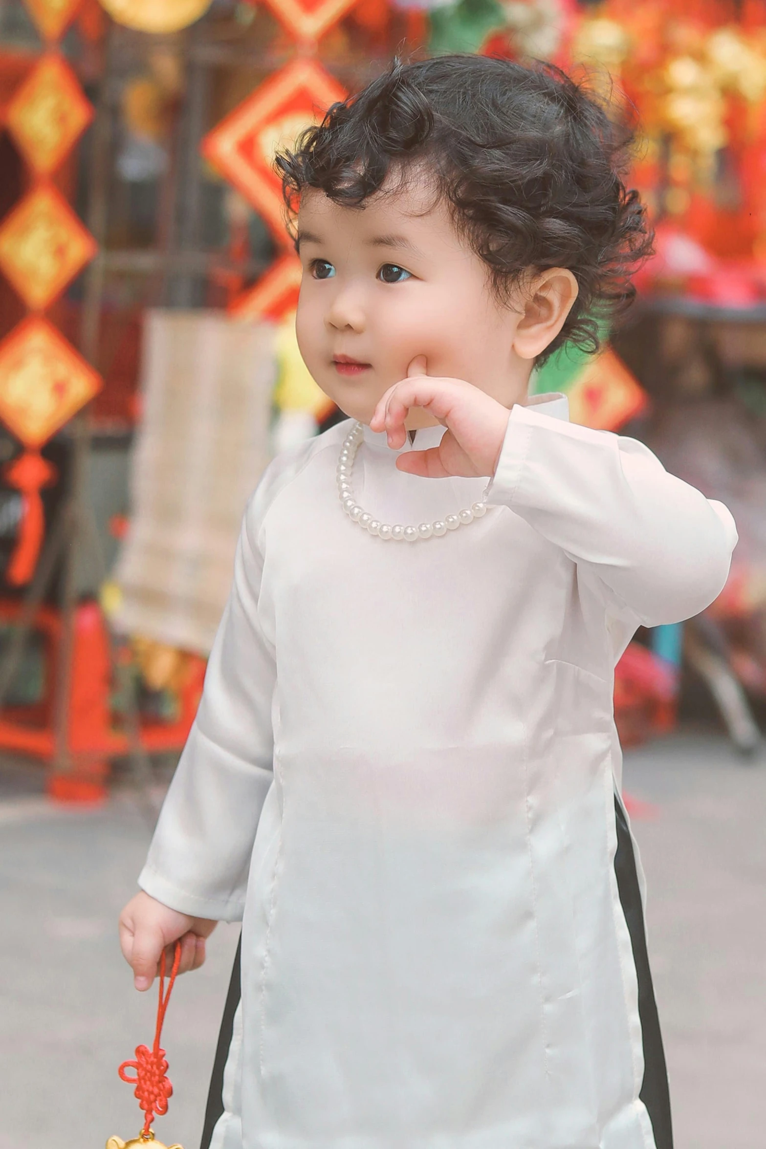 a child holds a flower shaped brooch while wearing a dress