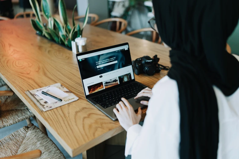 a person is sitting at a table with a laptop