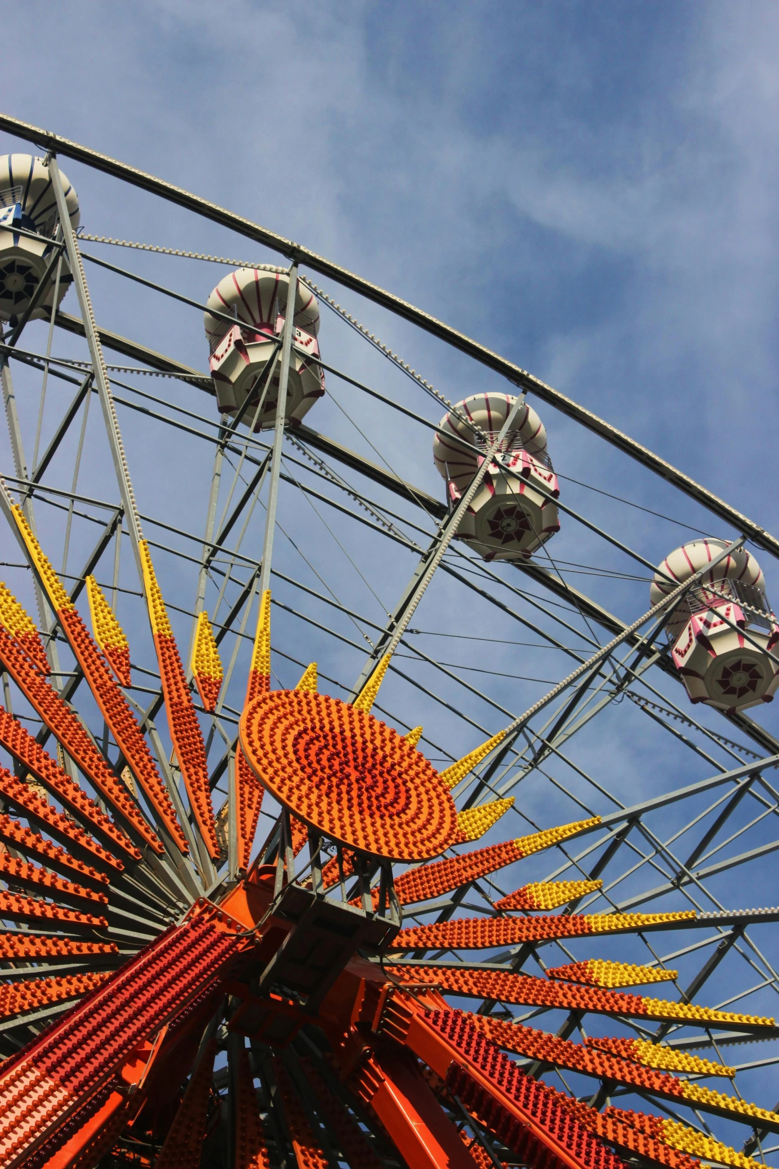 an orange, red and yellow ferris wheel against a blue sky