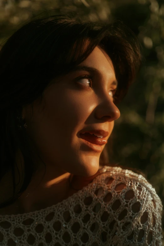 a woman standing outside near some trees looking off in the distance