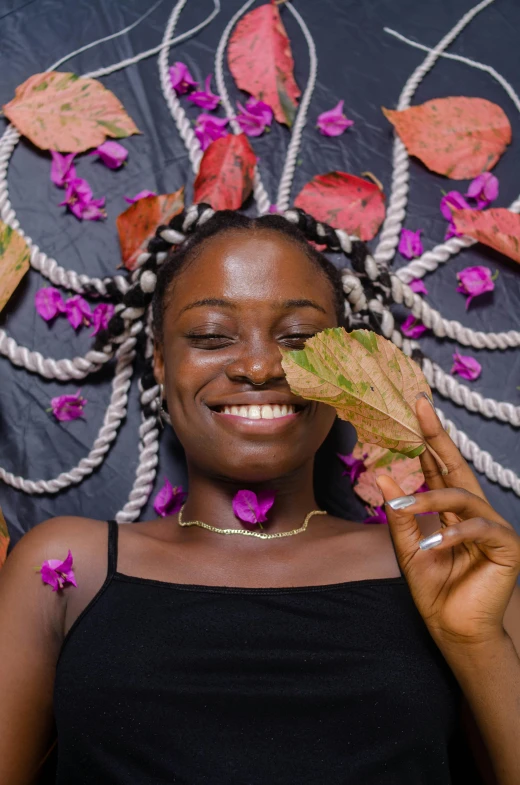 smiling black woman with a leaf laying on her head