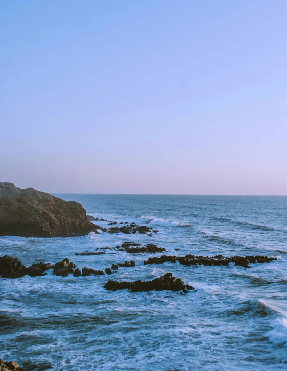 a man walking on a rocky beach near the water