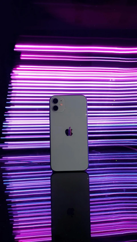 an iphone laying on top of a counter with colorful lights in the background