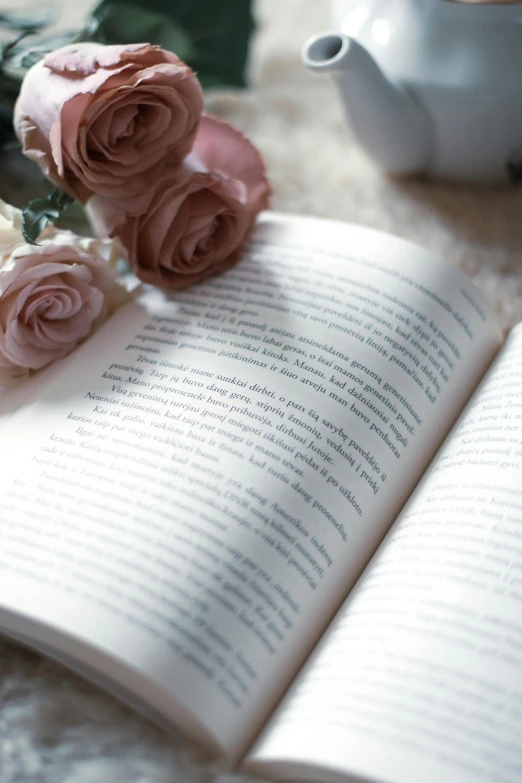 the book is open with some pink flowers and a kettle